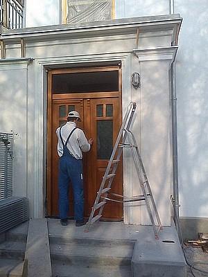 czlowiek montujacy drzwi wejsciowe